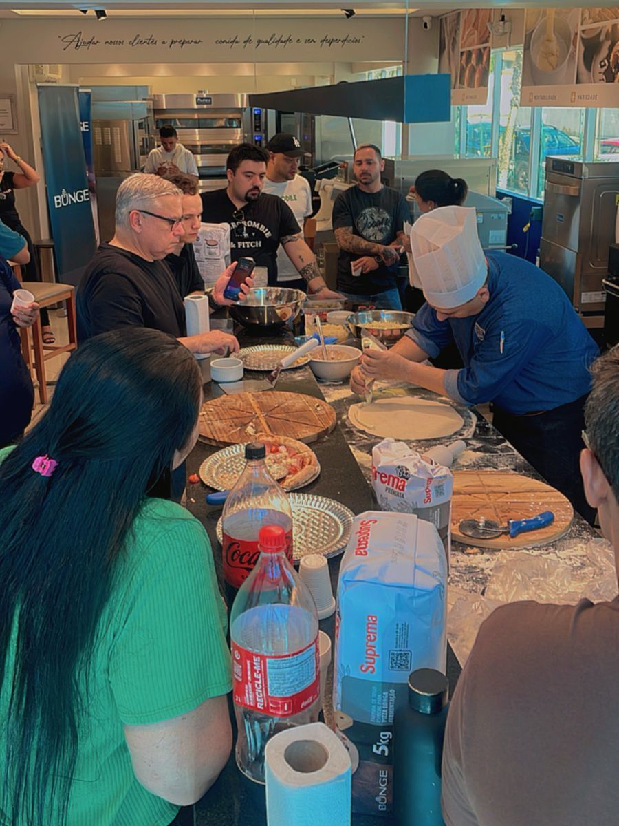 Um grupo de pessoas está sentado ao redor de uma mesa comendo pizza.