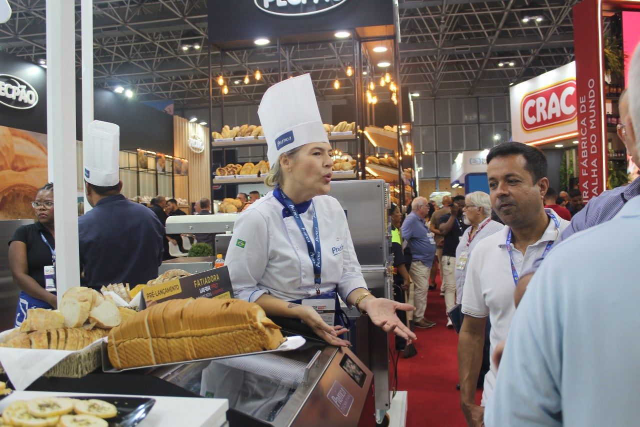 Uma mulher com chapéu de chef está conversando com um grupo de pessoas