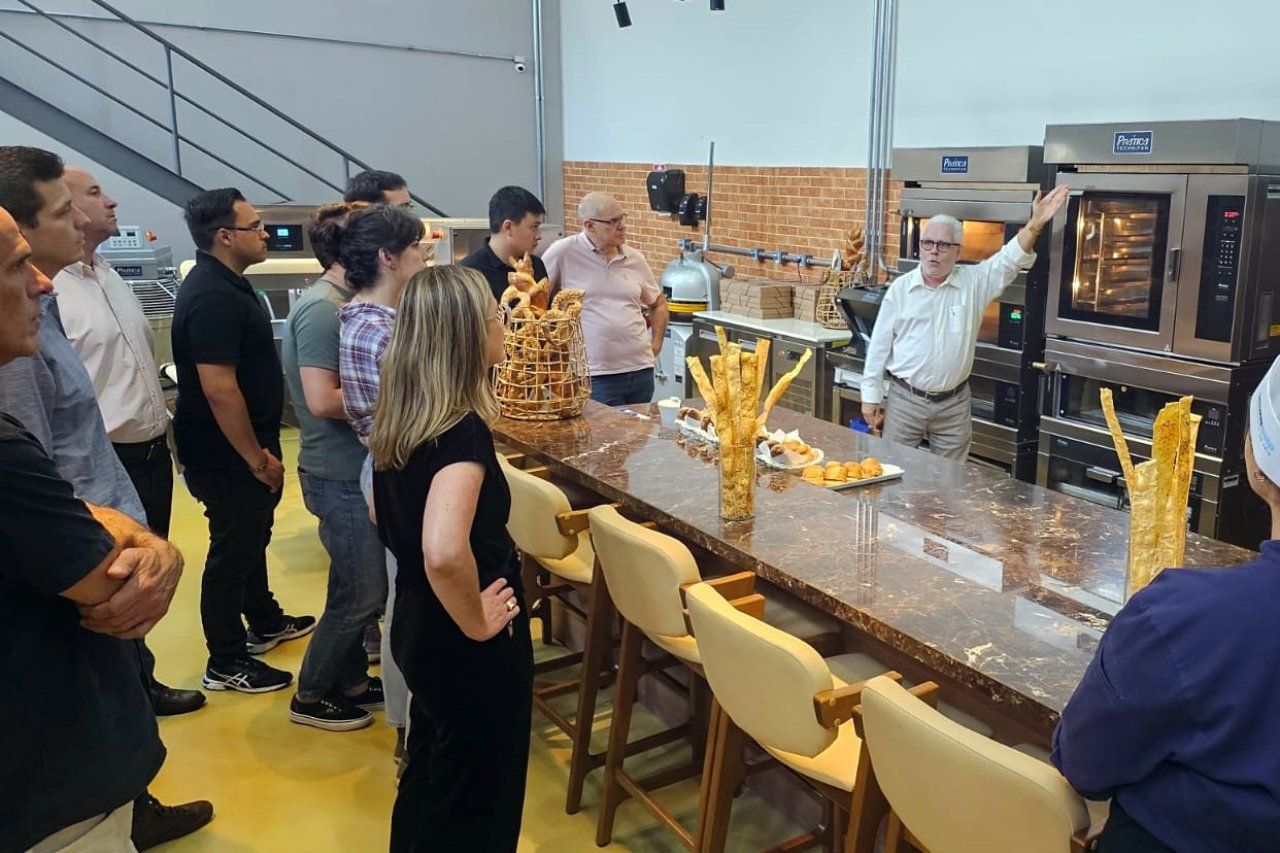 Um grupo de pessoas está em pé ao redor de um balcão na cozinha.
