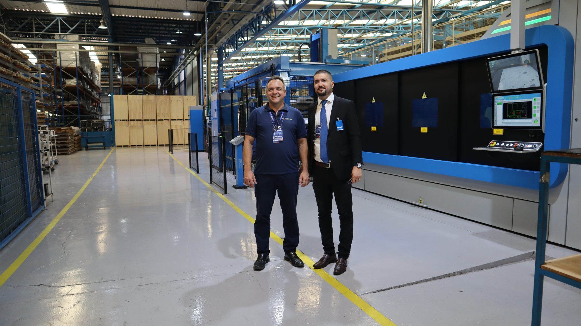 Dois homens estão parados um ao lado do outro em uma fábrica.