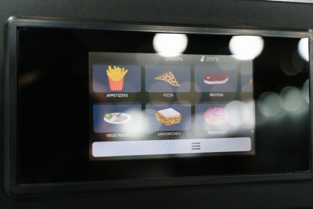 Uma tela exibe uma variedade de itens alimentares, incluindo batatas fritas, pizza e sanduíches