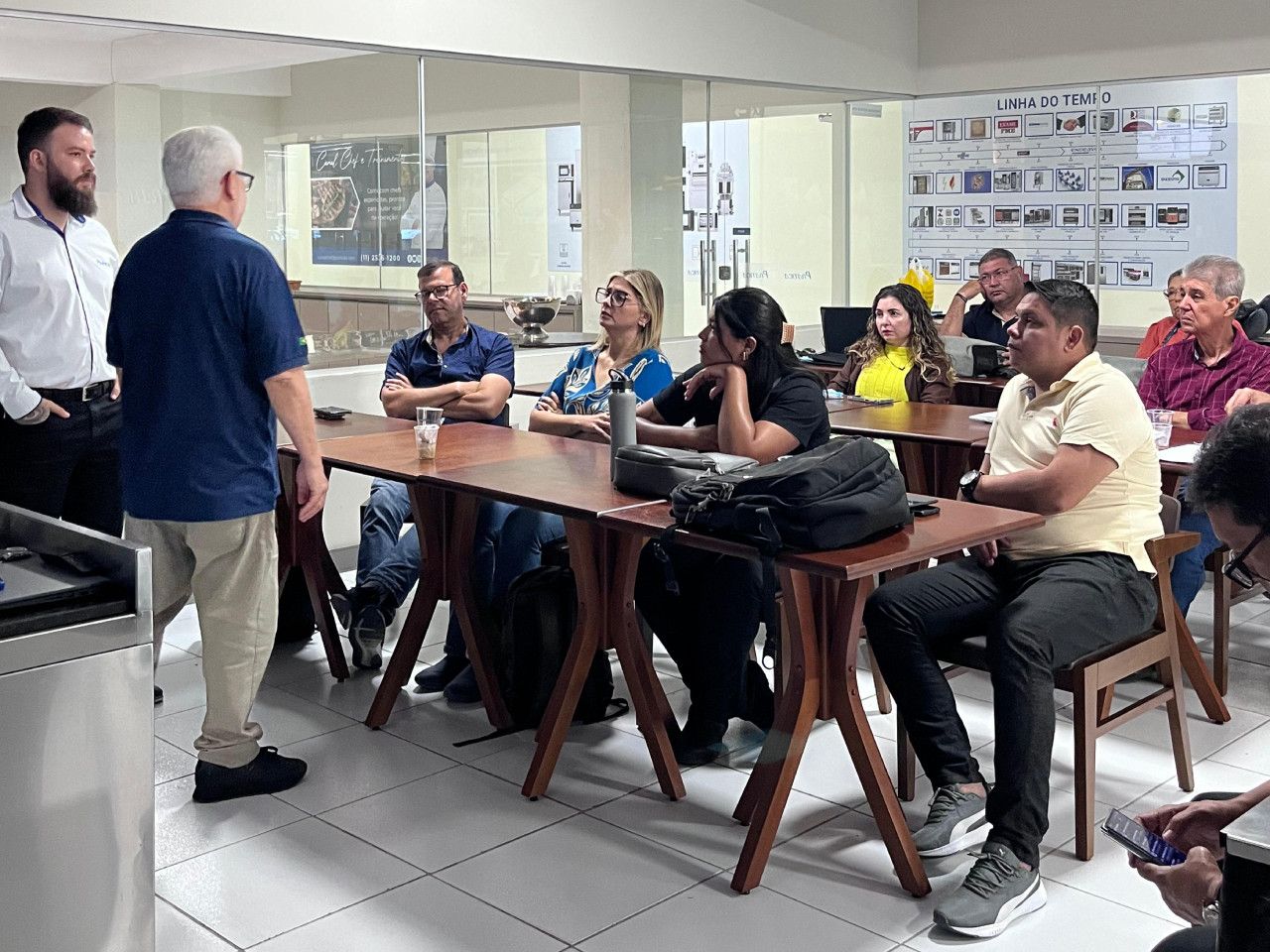 Um grupo de pessoas está sentado em mesas em uma sala.