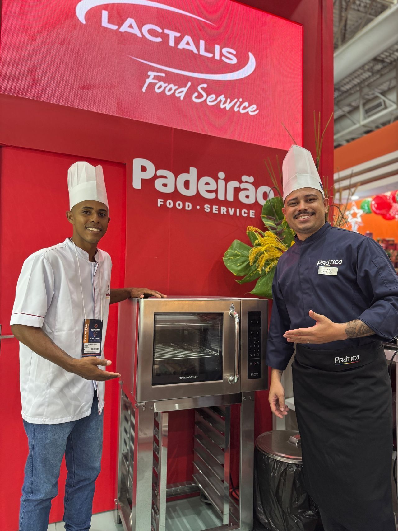 Dois chefs posam com um forno no estande da Lactalis Food Service. O fundo é vermelho e branco.
