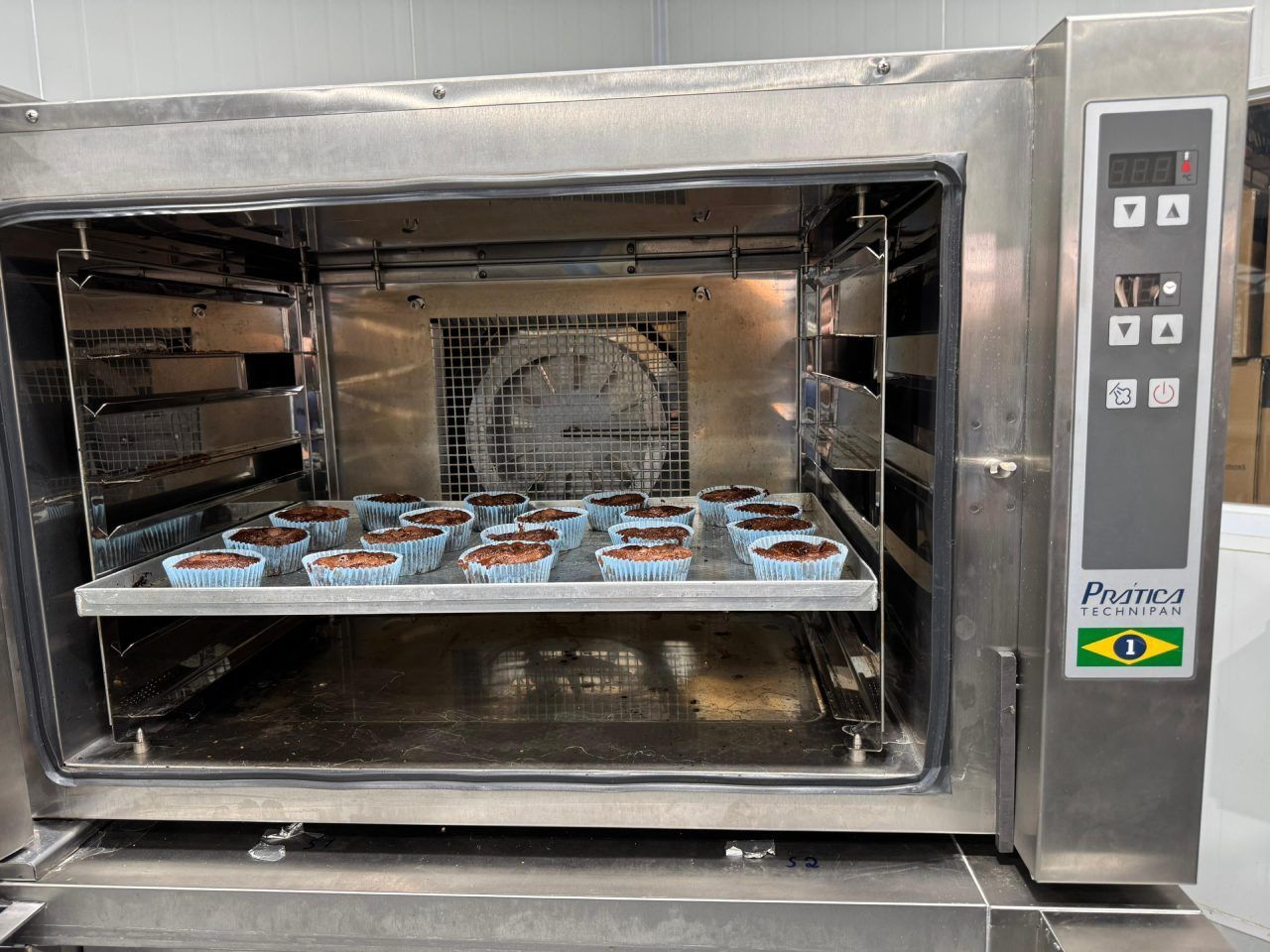 Um forno de aço inoxidável com uma bandeja de cupcakes dentro.