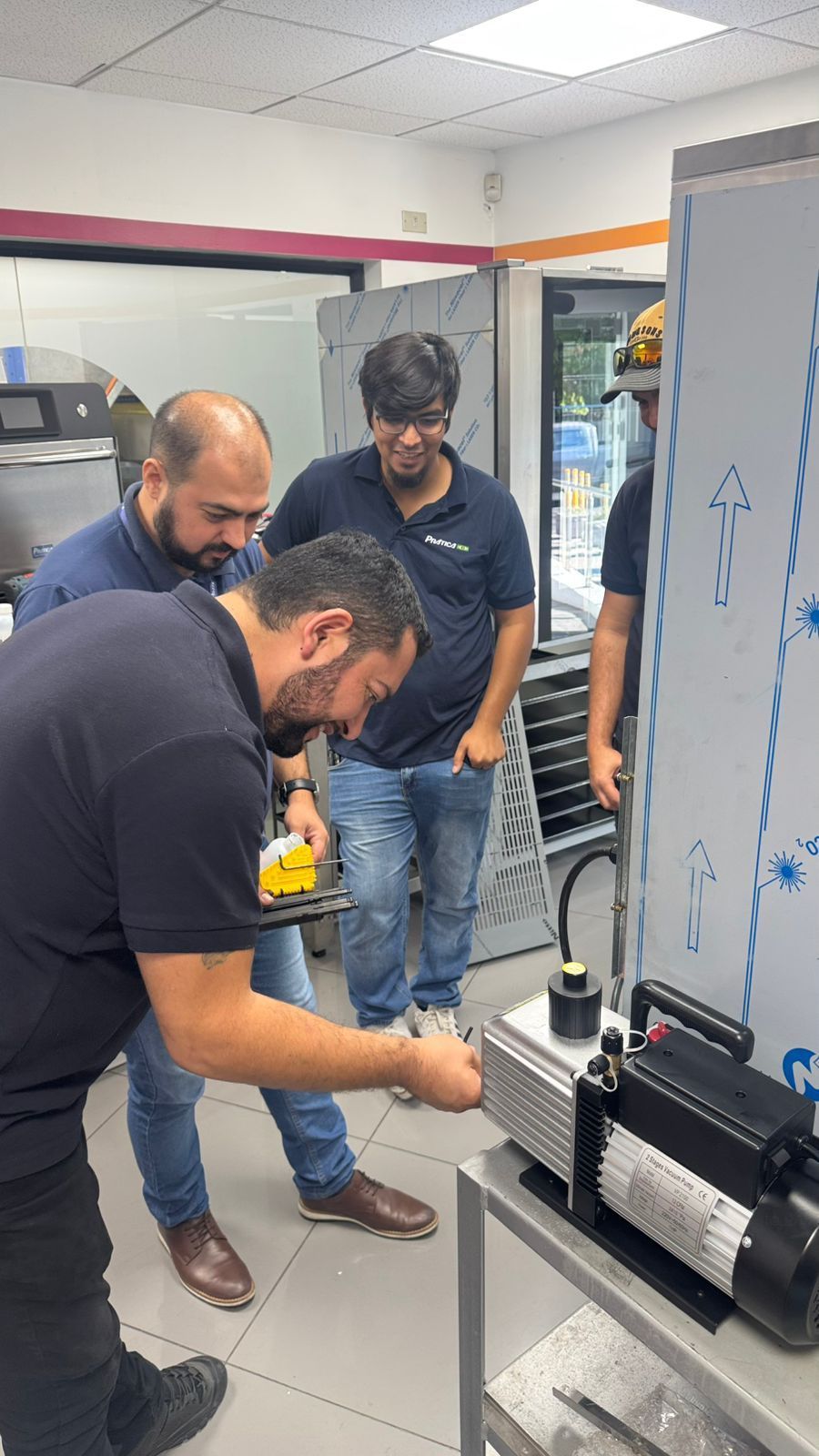 Homens inspecionando máquinas industriais em um ambiente comercial. Um dos homens aponta para um dispositivo.