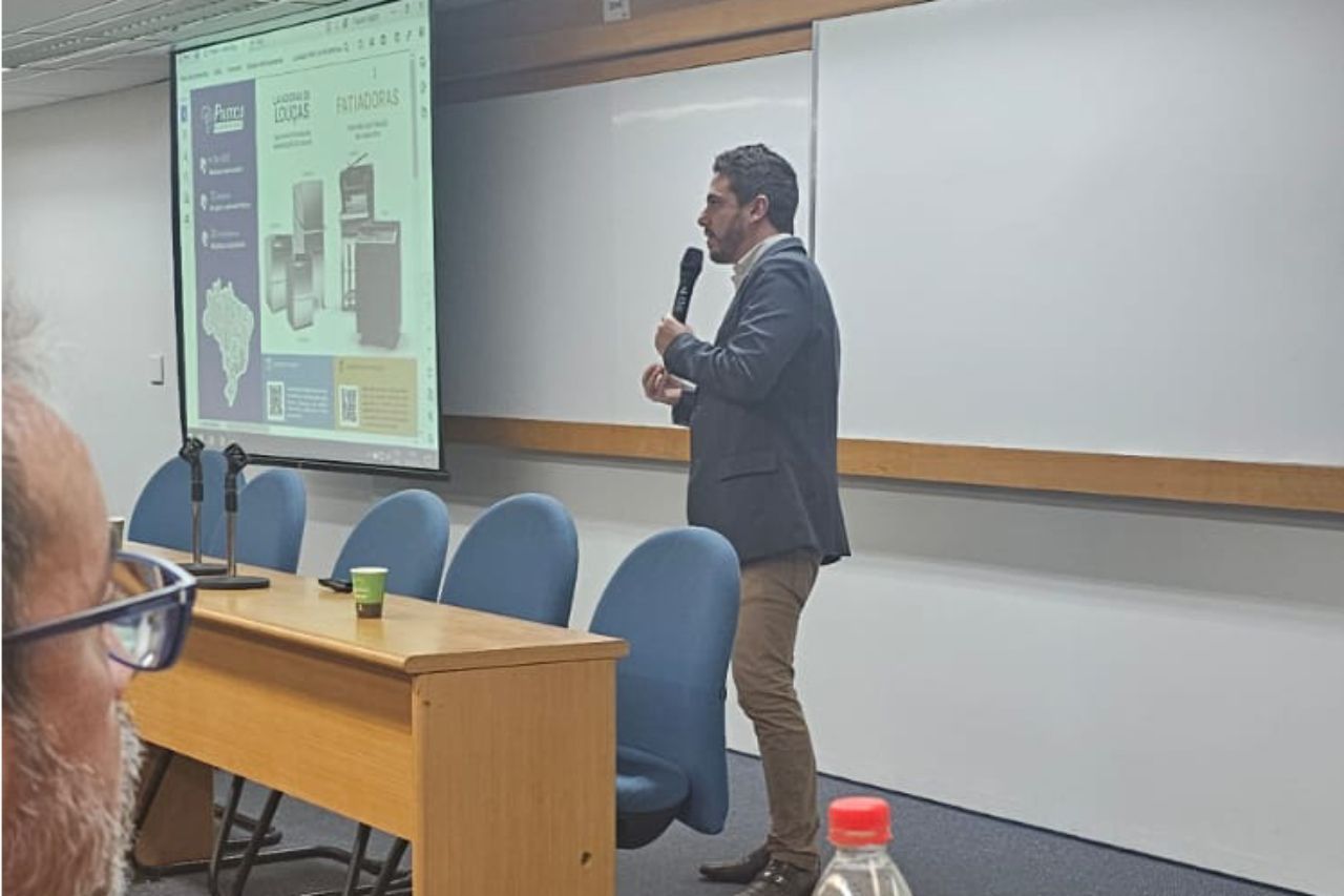 Um homem está em pé na frente de uma tela de projetor fazendo uma apresentação.