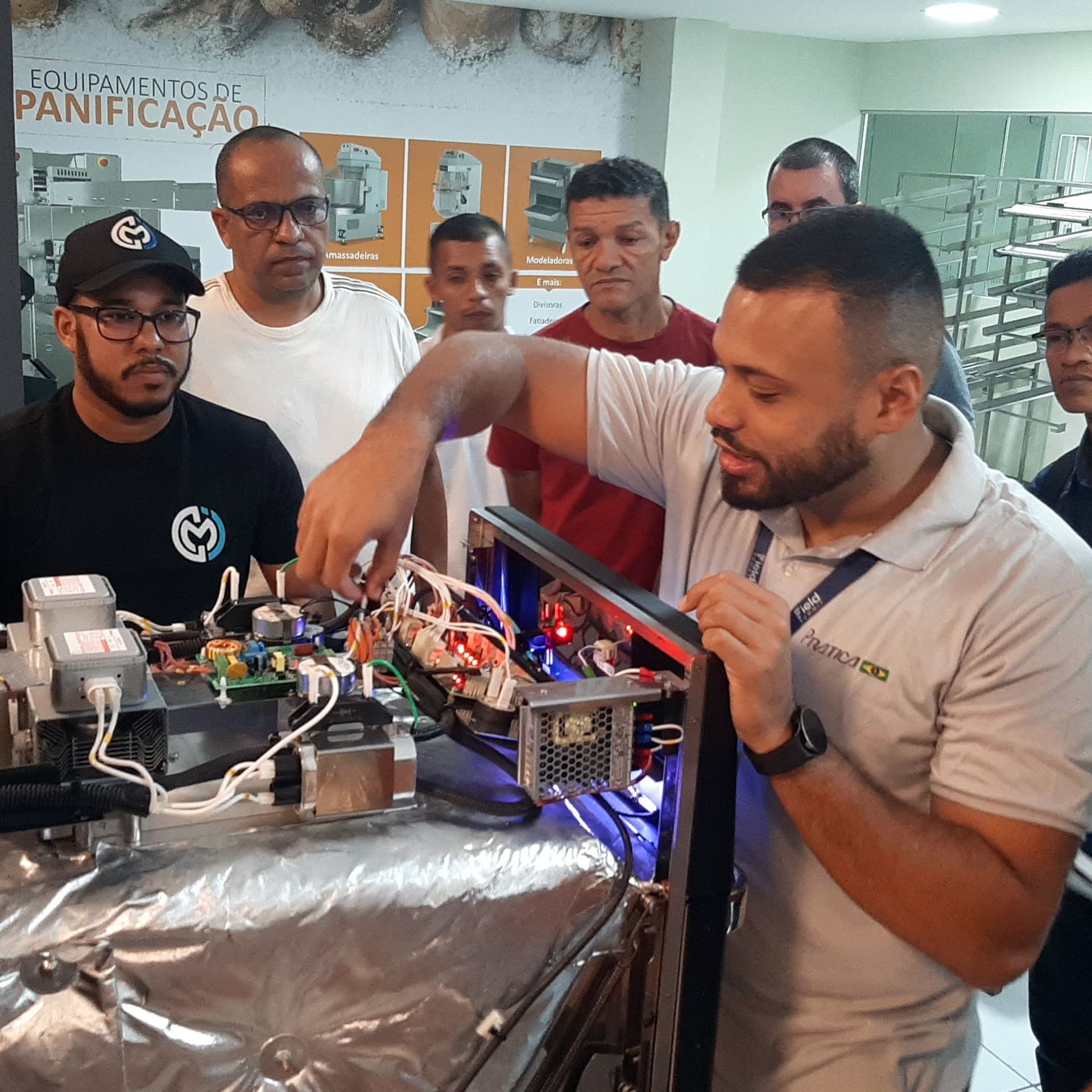 Um grupo de homens está trabalhando em uma máquina com uma placa atrás deles que diz panificação