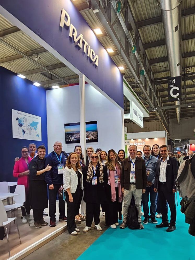 Grupo de pessoas posando em frente a um estande azul e branco da 