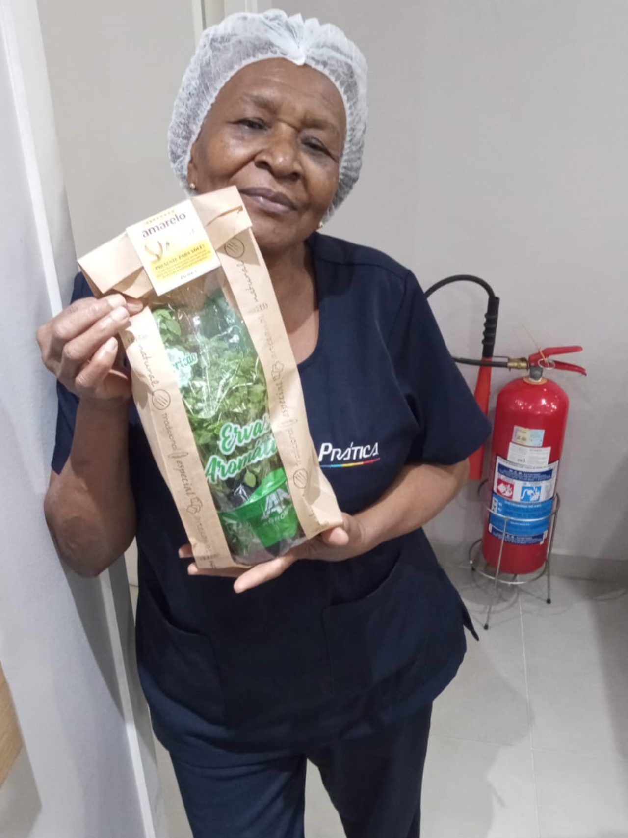 Uma mulher de uniforme está segurando um saco de ervas