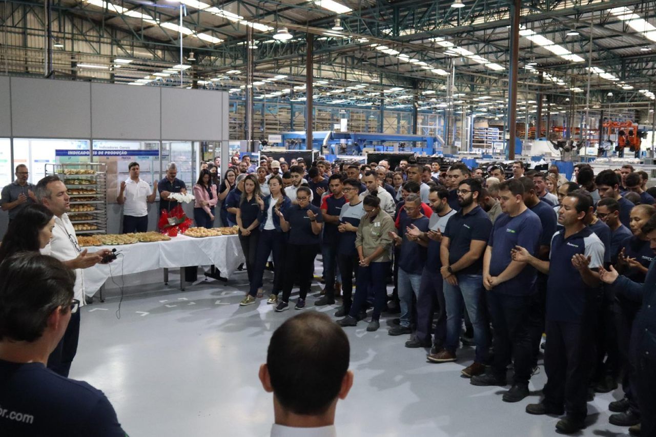 Um grande grupo de pessoas está em um armazém.