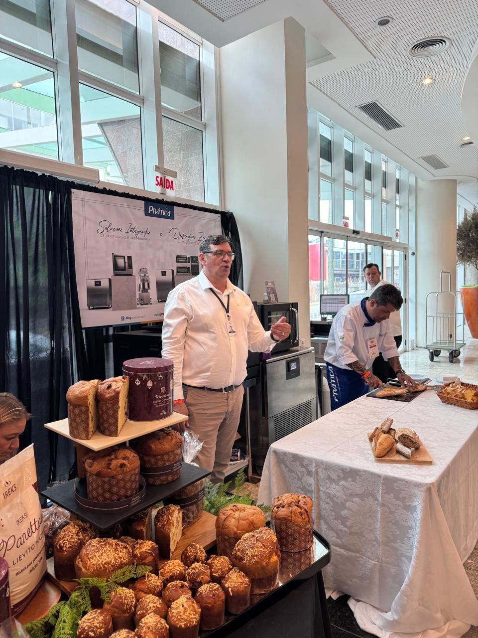 Um homem está de pé em frente a uma mesa cheia de comida.