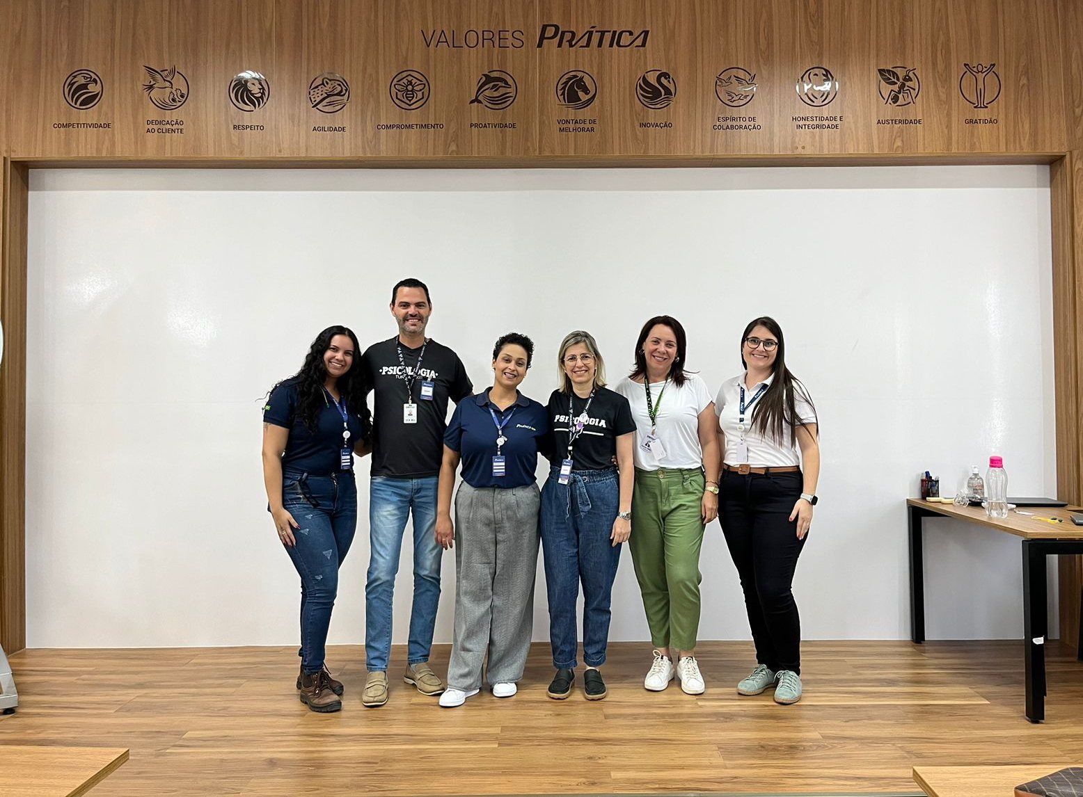 Um grupo de pessoas está posando para uma foto em frente a um quadro branco.