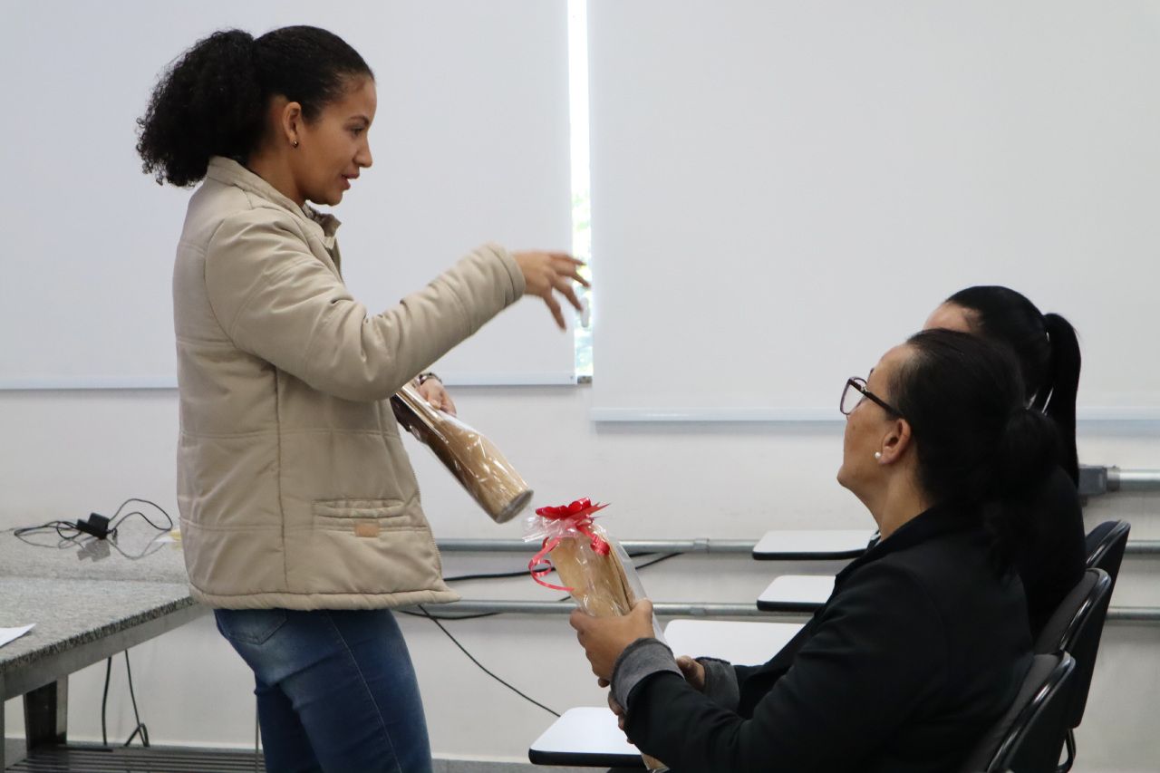 Uma mulher está de pé ao lado de outra mulher em uma sala de aula segurando uma garrafa.