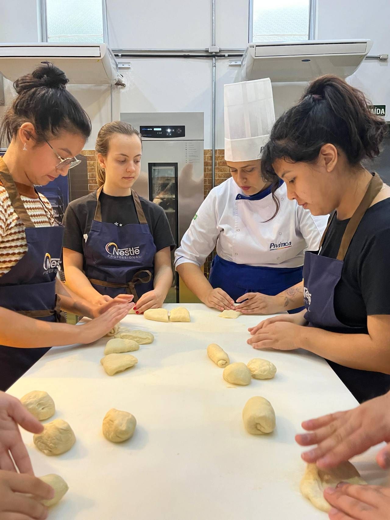 Um grupo de pessoas está sentado ao redor de uma mesa fazendo massa.