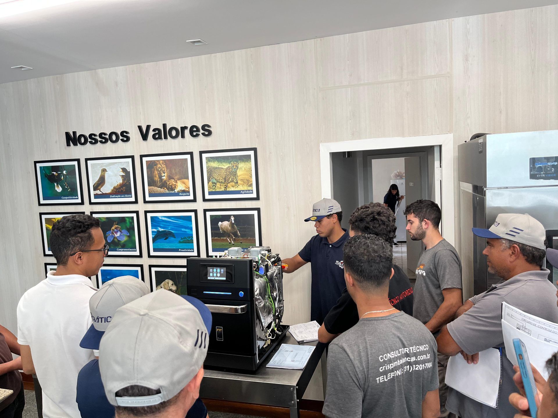 Um grupo de pessoas está em pé ao redor de uma máquina em uma sala.