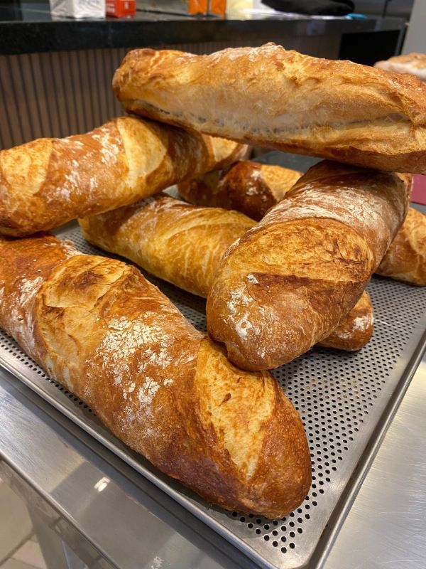 Um monte de baguetes empilhadas umas sobre as outras em uma bandeja.