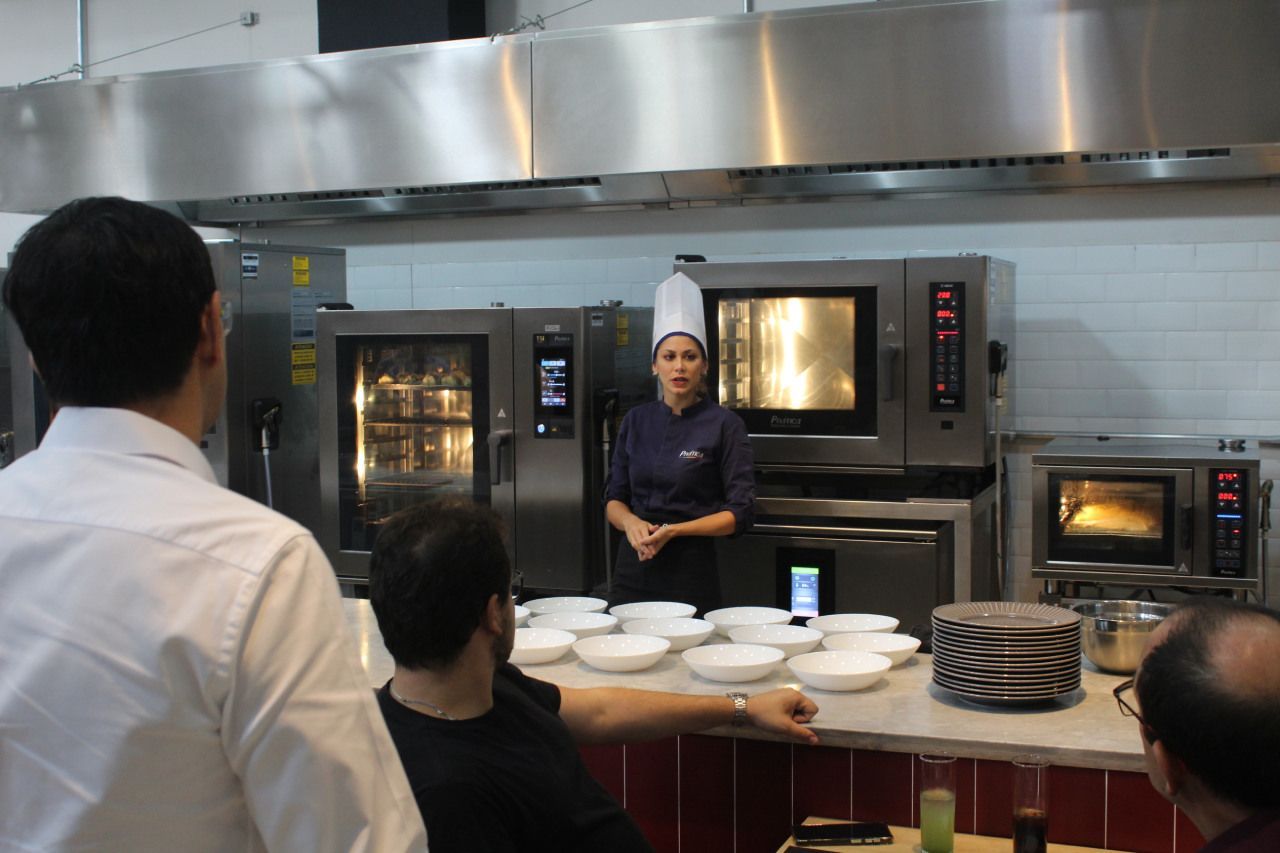 Uma mulher com chapéu de chef está parada na cozinha