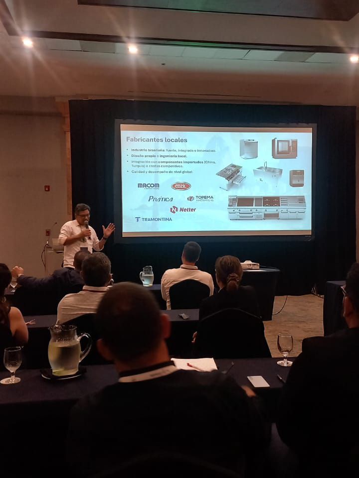 Homem apresentando em conferência, slide sobre telemática. Público sentado, olhando para a tela.