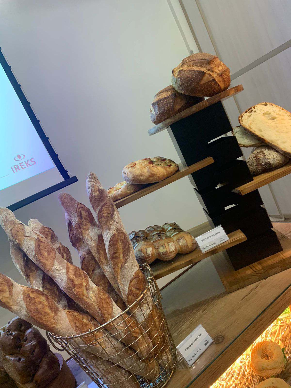 Um monte de pão está sobre uma mesa em frente a uma tela de projetor.