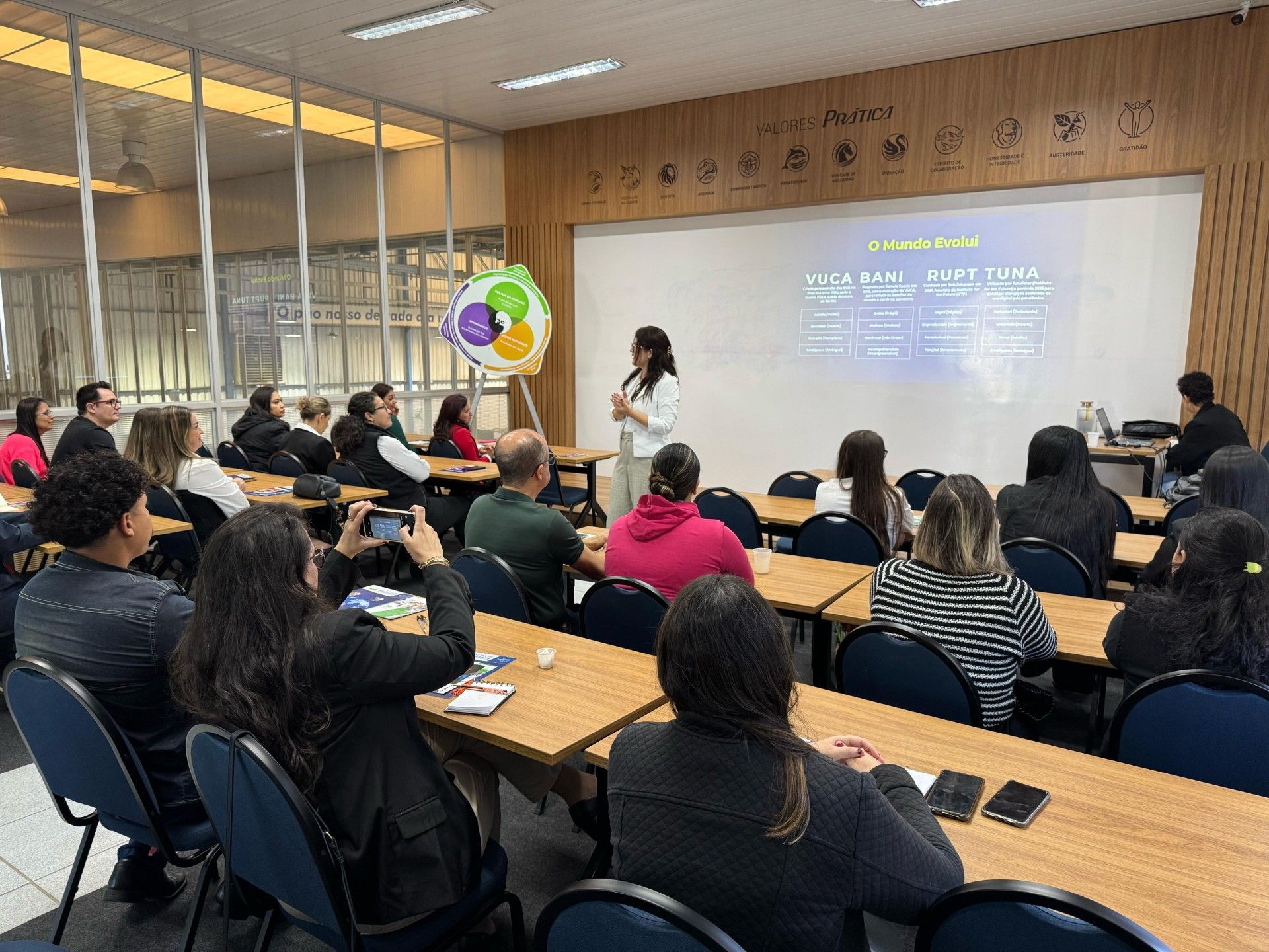 Uma mulher está fazendo uma apresentação para um grupo de pessoas em uma sala de aula.