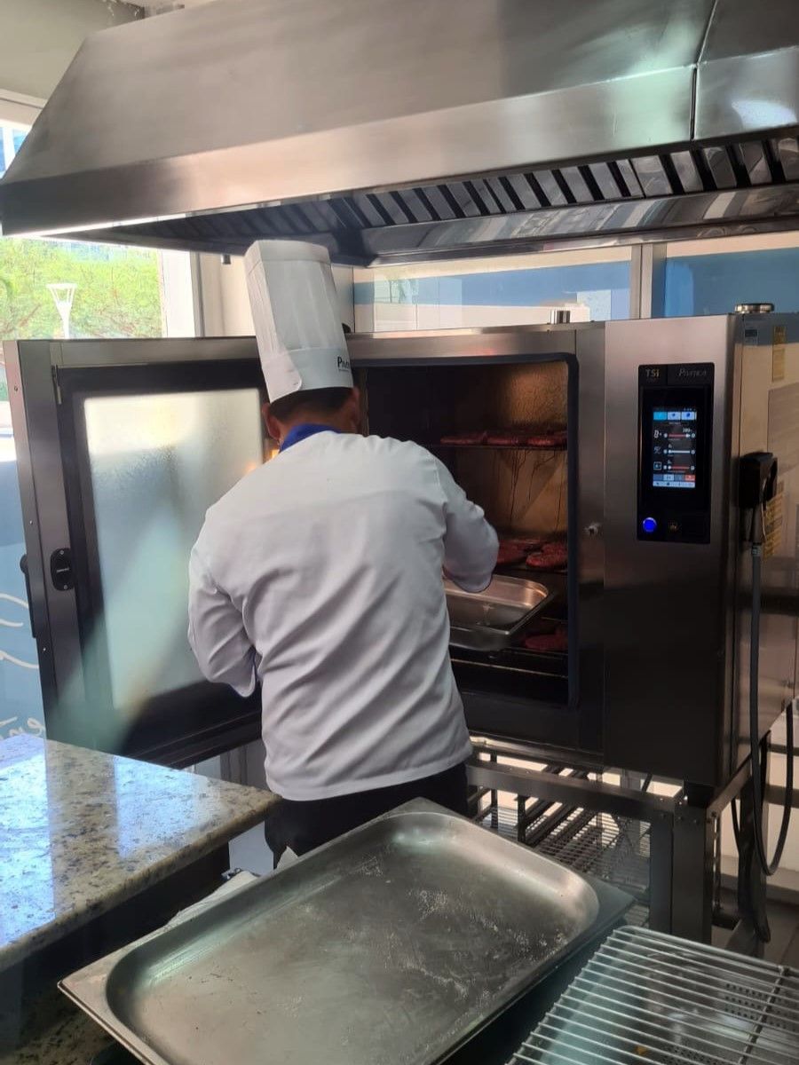 Um chef está colocando comida em um forno em uma cozinha