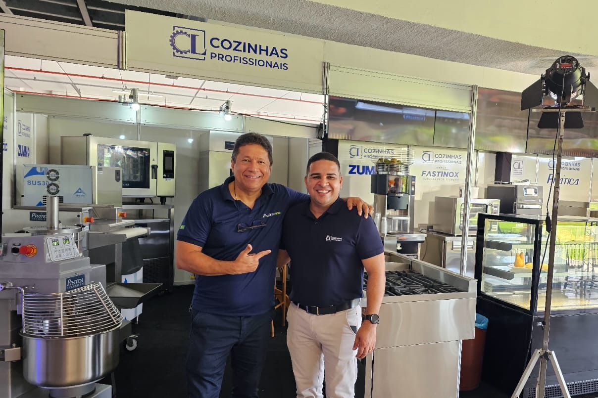 Dois homens estão posando para uma foto em uma cozinha.