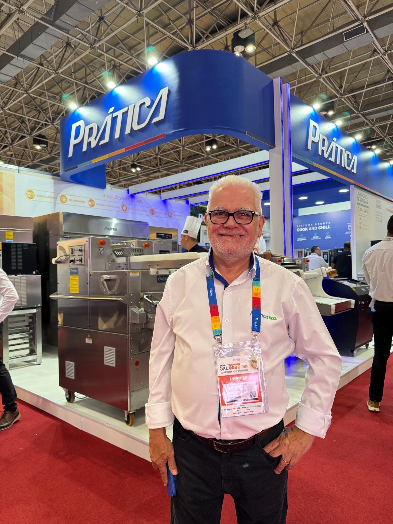 Um homem está parado em frente a um estande em uma convenção.