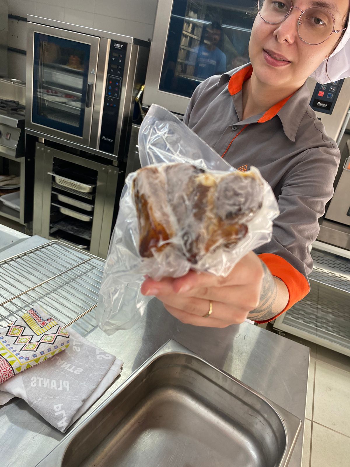 Uma mulher segura um pedaço de comida em um saco plástico na cozinha.
