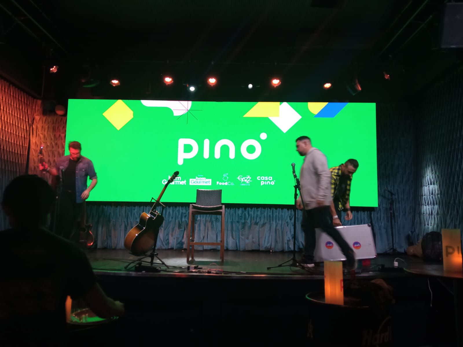 Um grupo de pessoas está em pé em um palco em frente a uma tela grande que diz pino