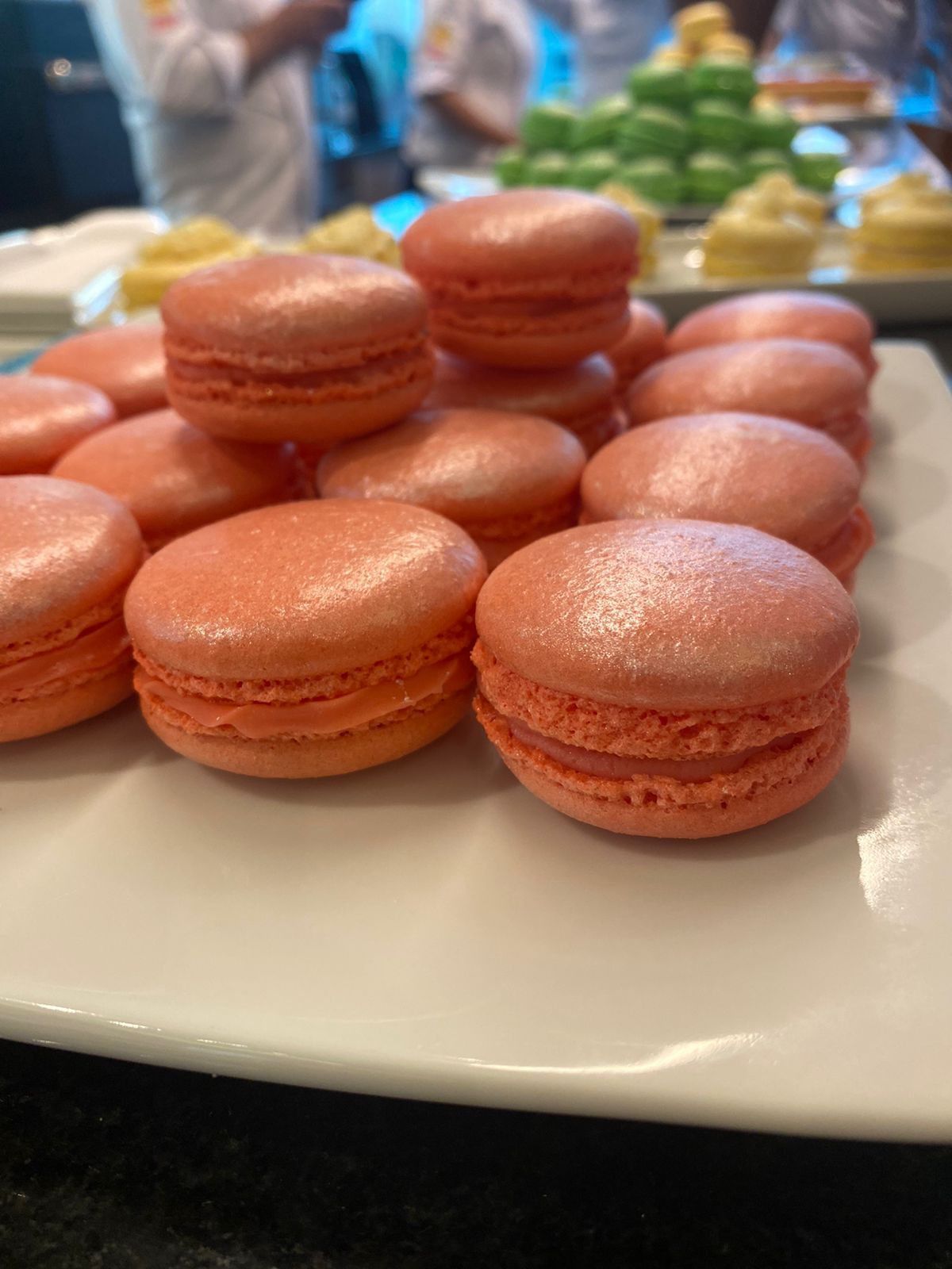 Um prato branco coberto com macarons rosa sobre uma mesa.