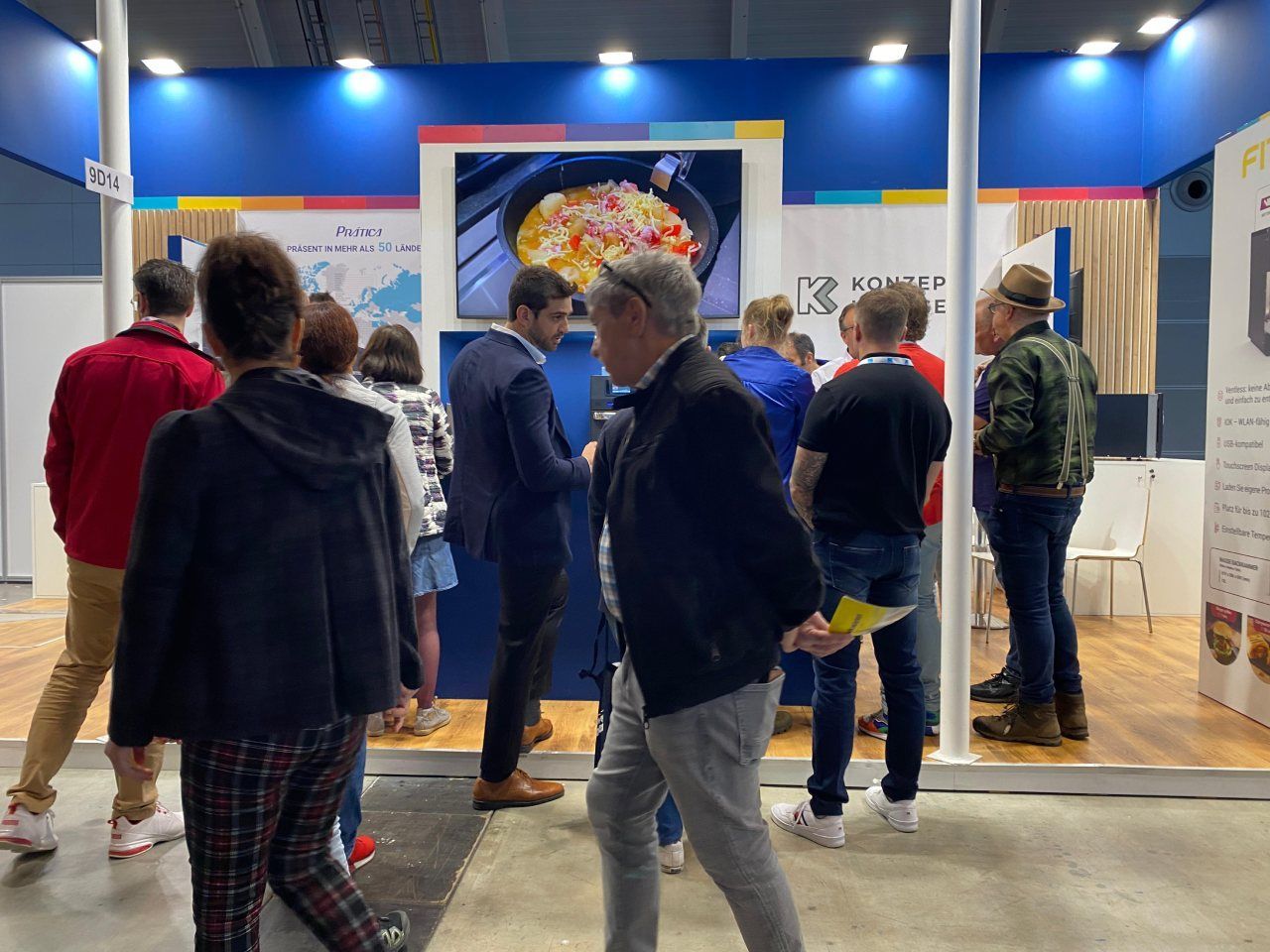 Um grupo de pessoas está em volta de um estande em uma convenção.