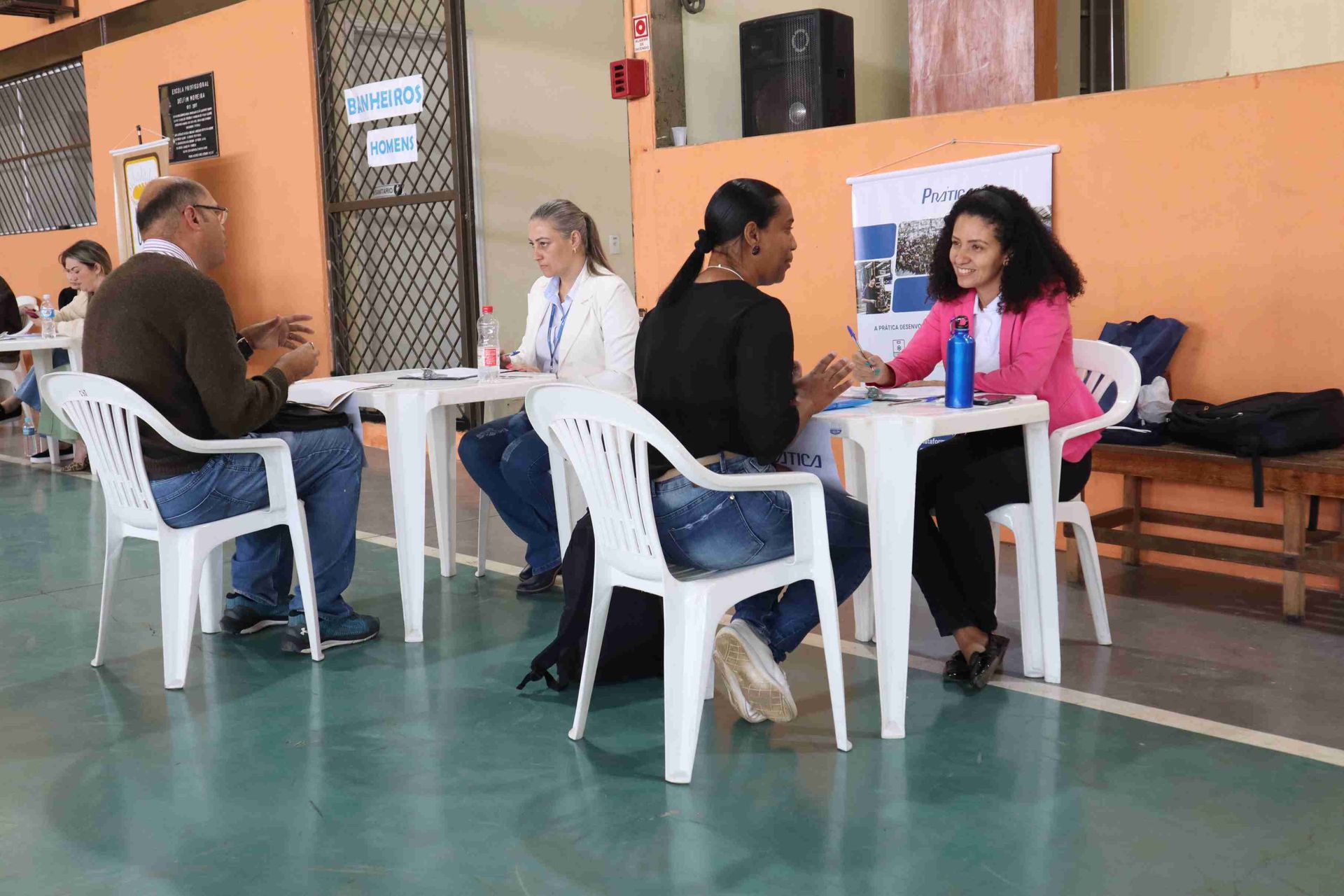 Um grupo de pessoas está sentado em mesas em uma sala.