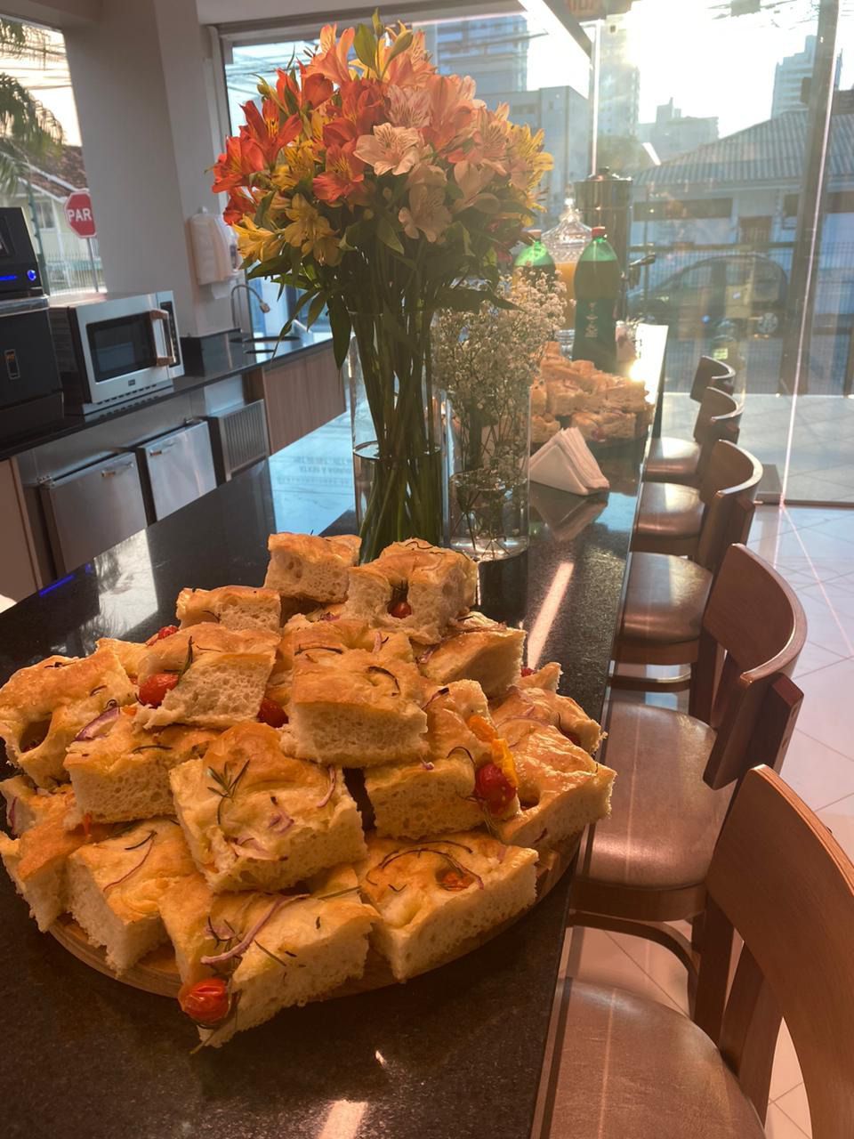 Uma bandeja de comida está sobre uma mesa ao lado de um vaso de flores.