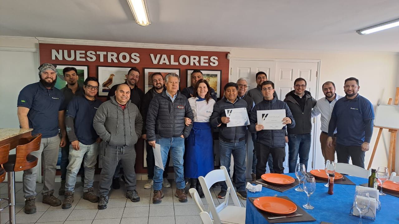 Um grupo de pessoas está posando para uma foto em frente a uma mesa.