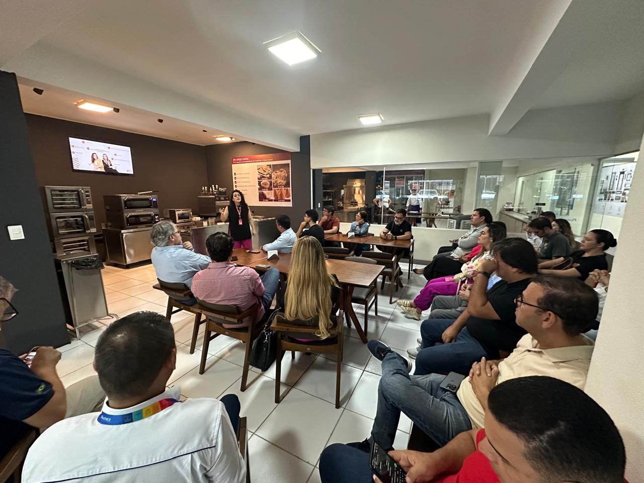 Um grupo de pessoas está sentado em mesas em uma sala.