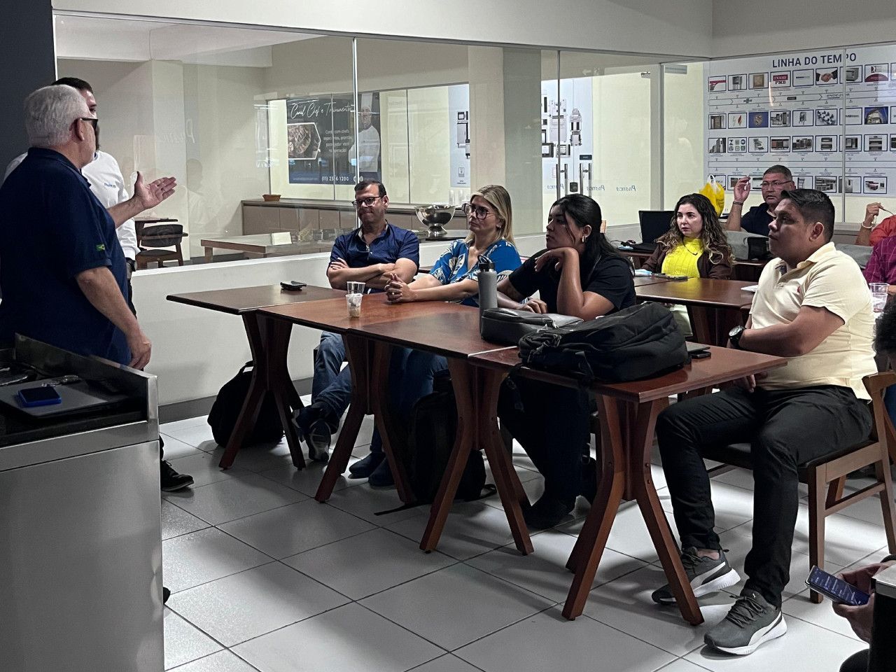 Um grupo de pessoas está sentado em mesas em uma sala.