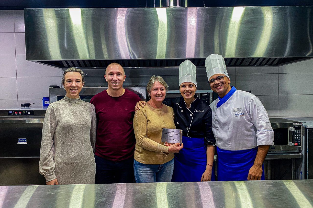 Um grupo de pessoas está posando para uma foto em uma cozinha.