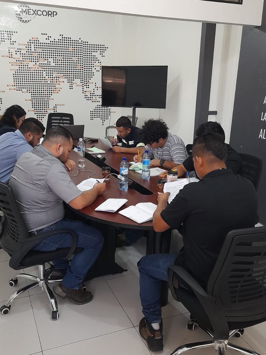 Um grupo de pessoas está sentado ao redor de uma mesa em uma sala de conferências.