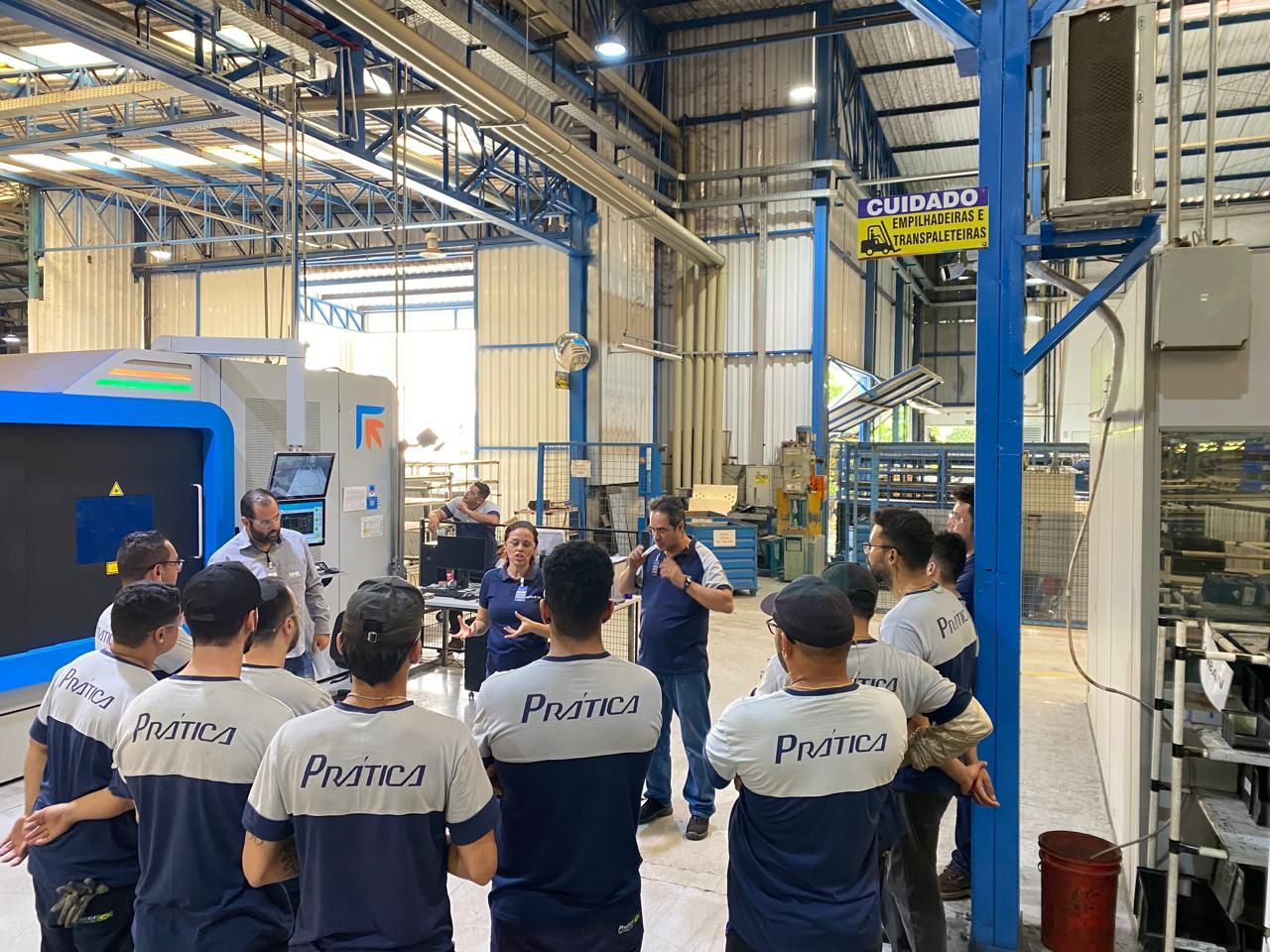 Um grupo de pessoas está em uma fábrica conversando entre si.