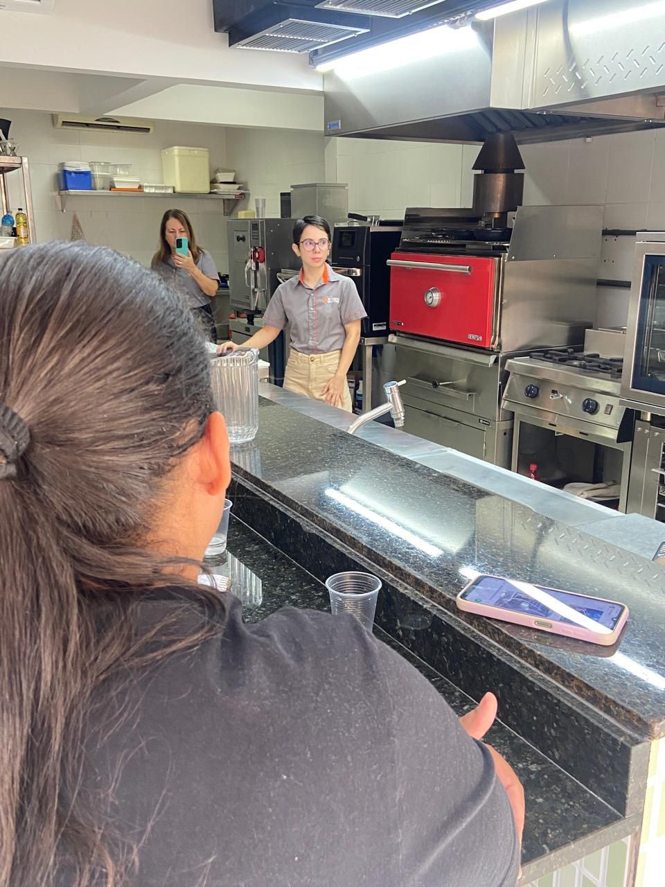 Uma mulher está sentada em um balcão na cozinha com um telefone nele.