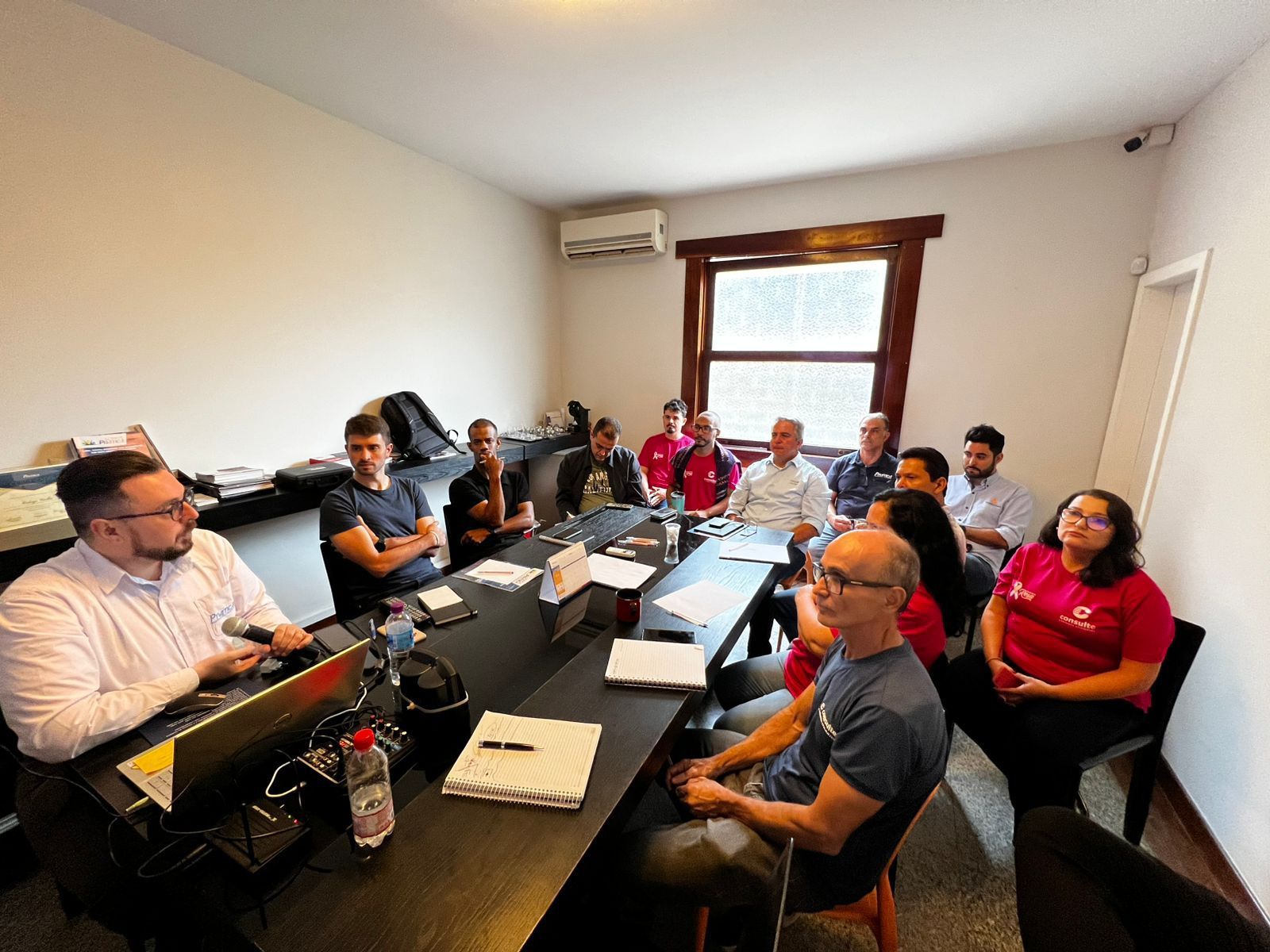 Um grupo de pessoas está sentado ao redor de uma mesa em uma sala de conferências.