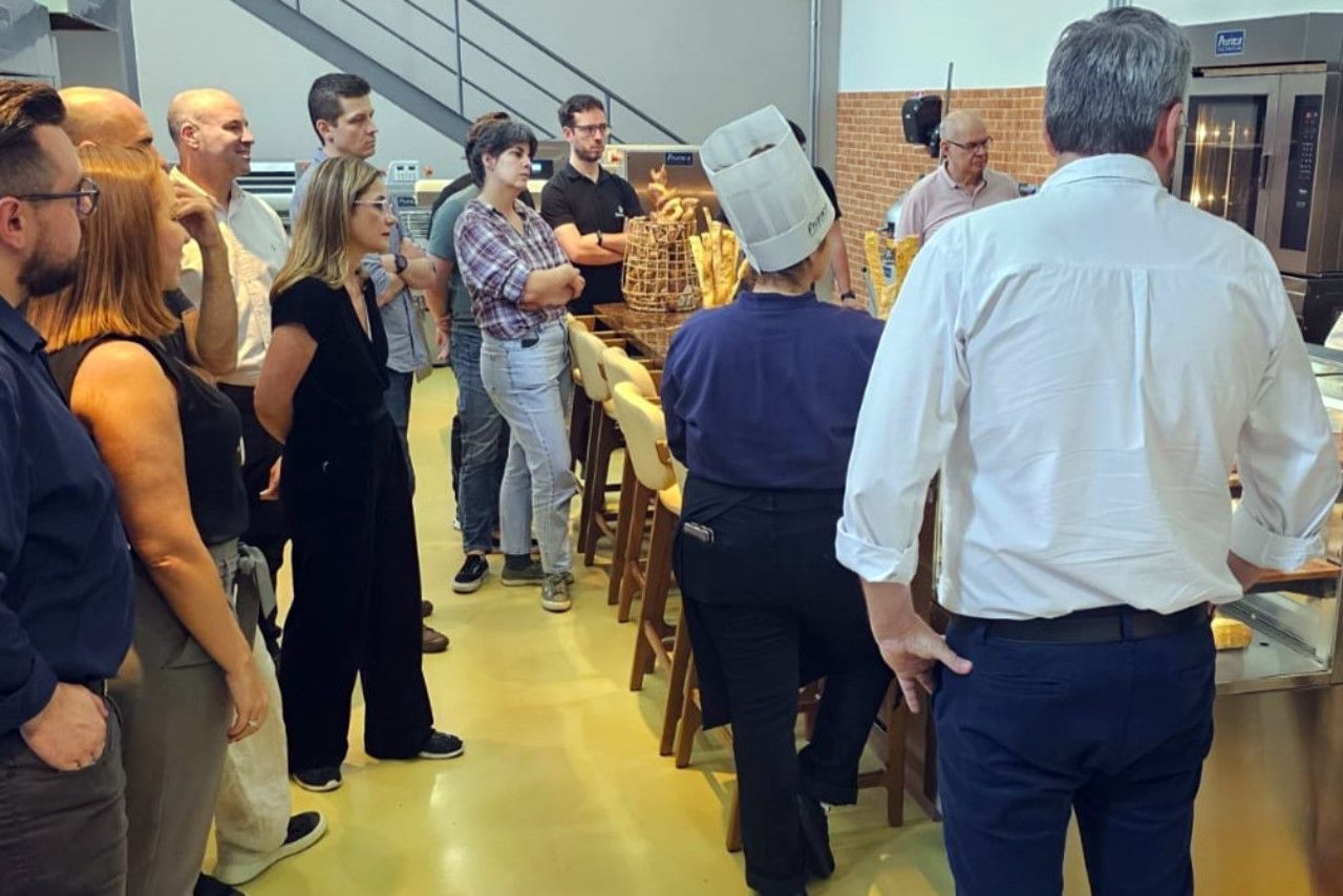 Um grupo de pessoas em pé em uma sala com um homem usando um chapéu de chef