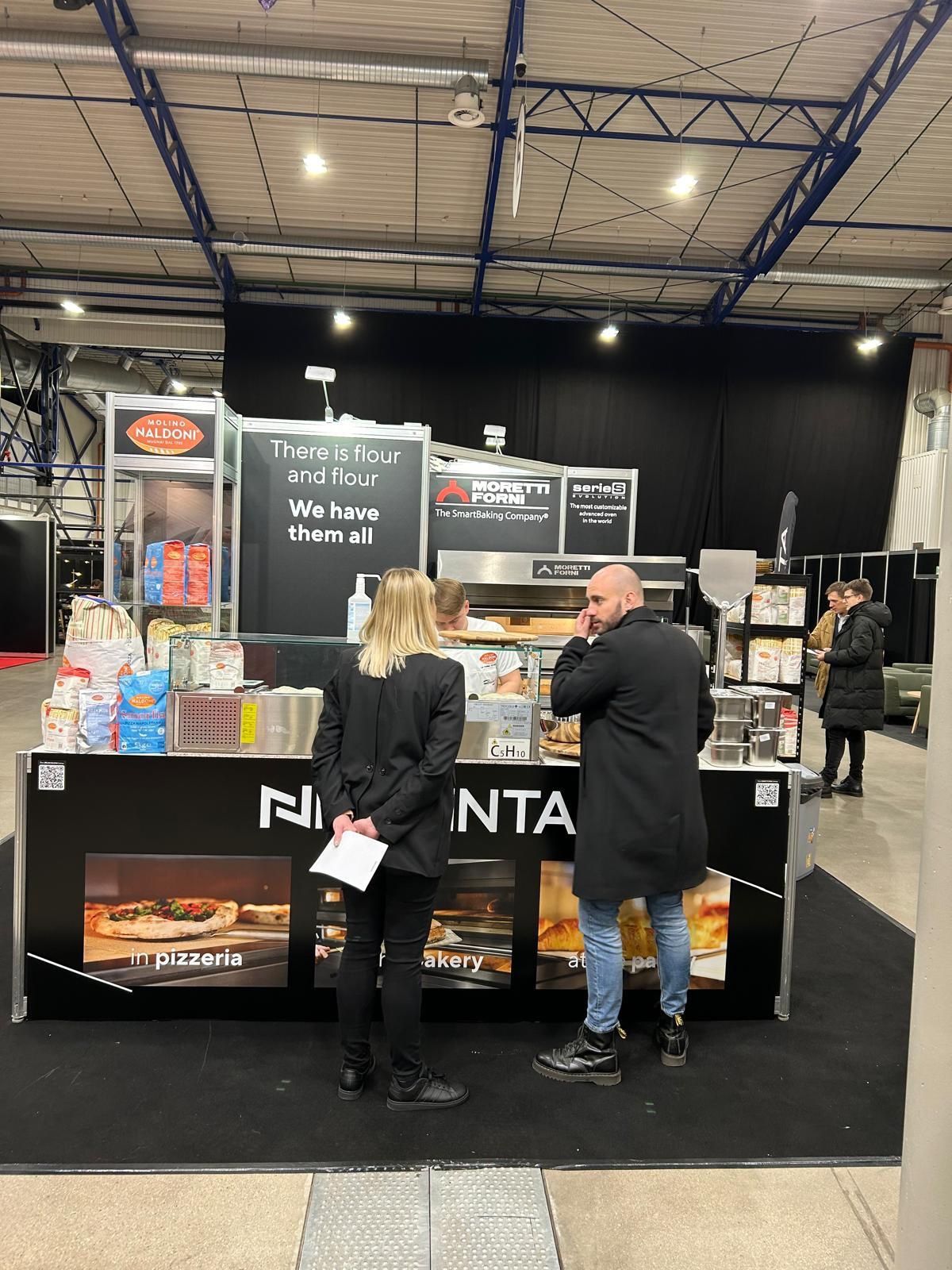 Um homem e uma mulher estão em frente a uma barraca de comida.