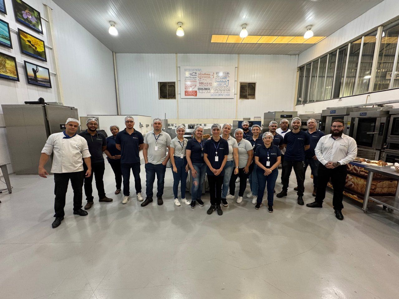 Um grupo de pessoas está posando para uma foto em uma sala grande.