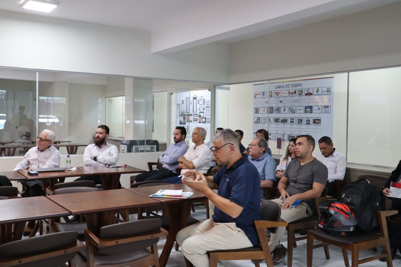 Um grupo de pessoas está sentado em mesas em uma sala.