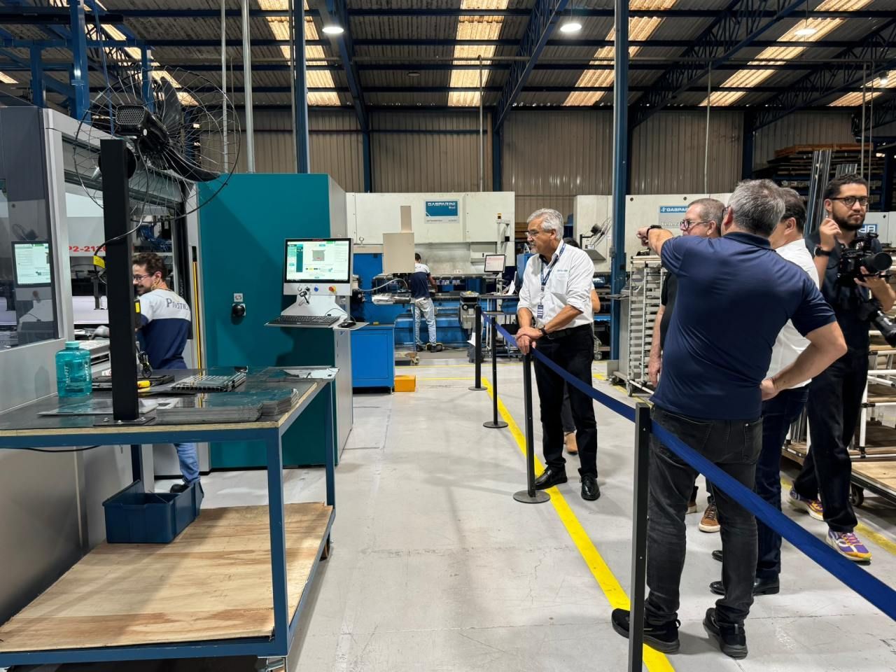 Um grupo de homens está em uma fábrica conversando entre si.