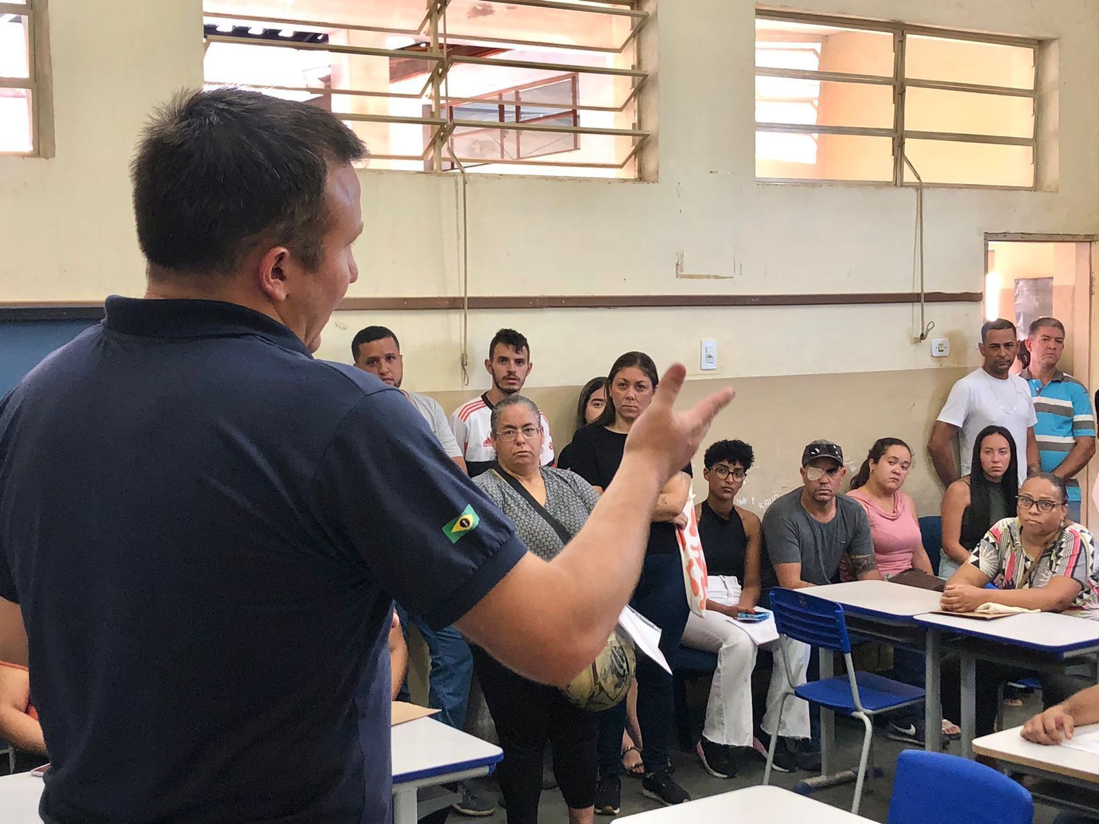 Um homem está conversando com um grupo de pessoas em uma sala de aula.
