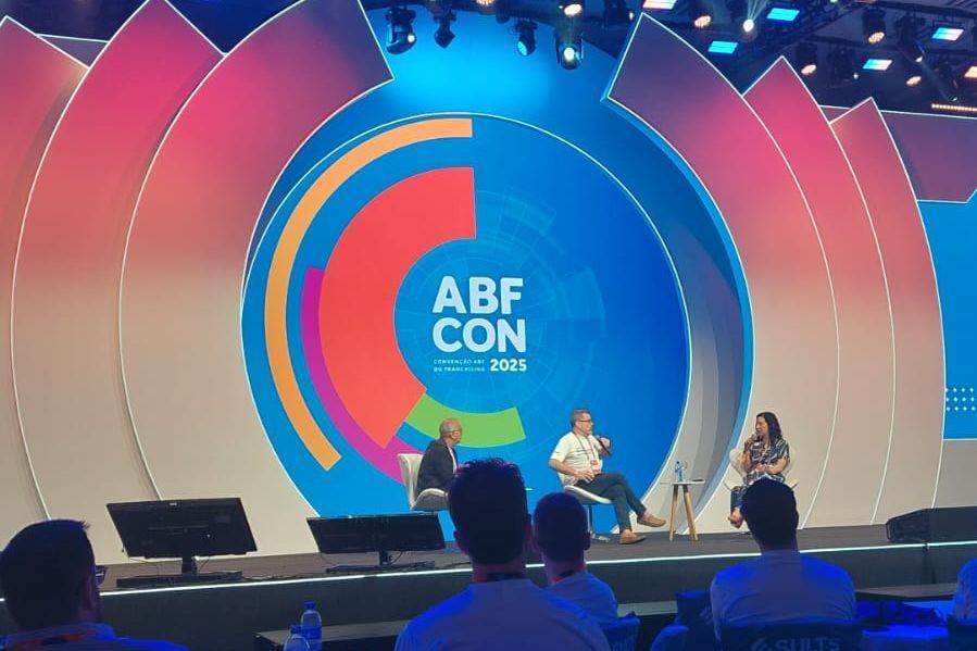 Painelistas no palco da ABF CON 2019, com um cenário colorido e público.