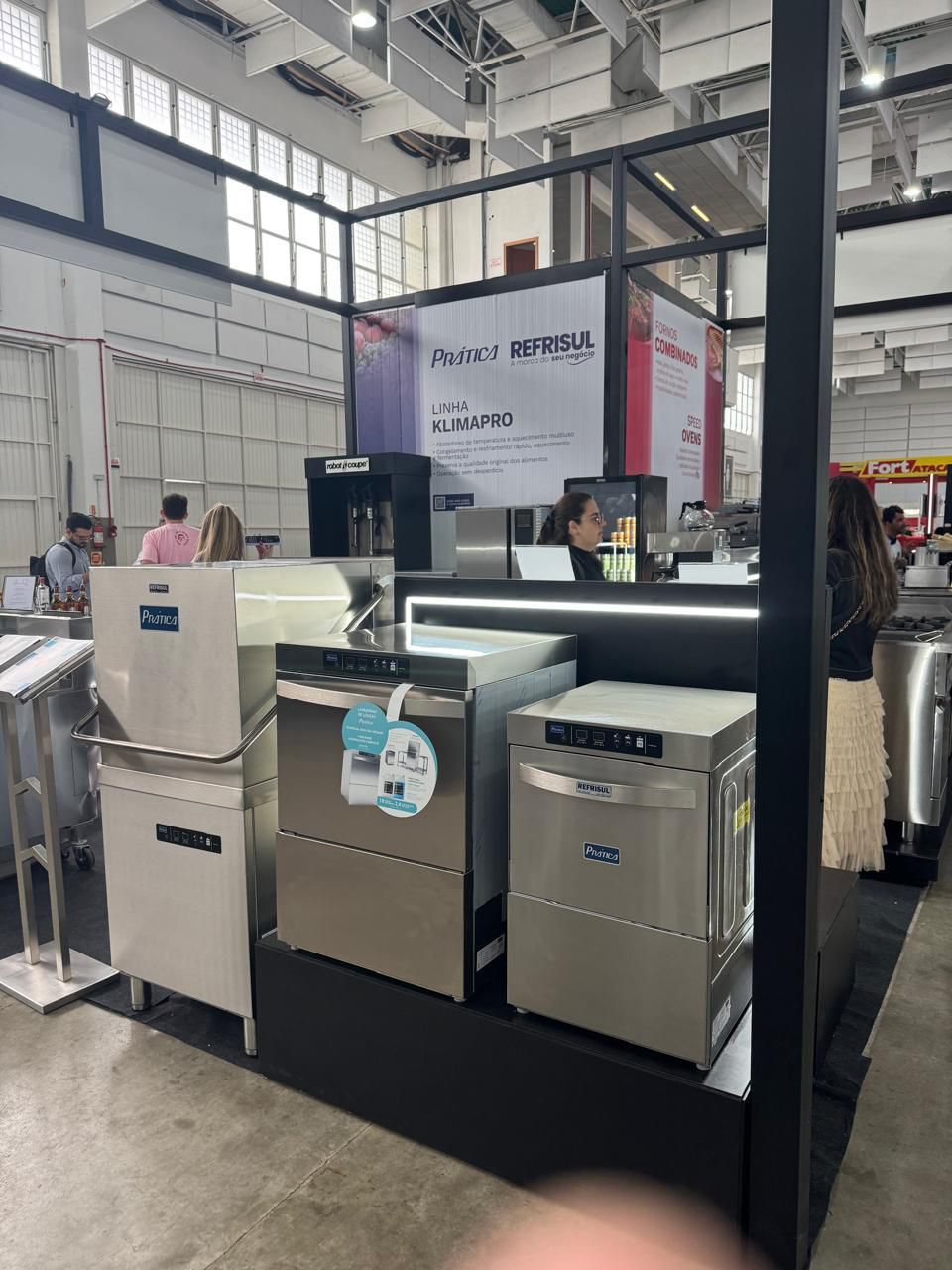 Uma exposição de máquinas de lavar louça de aço inoxidável em uma feira comercial.