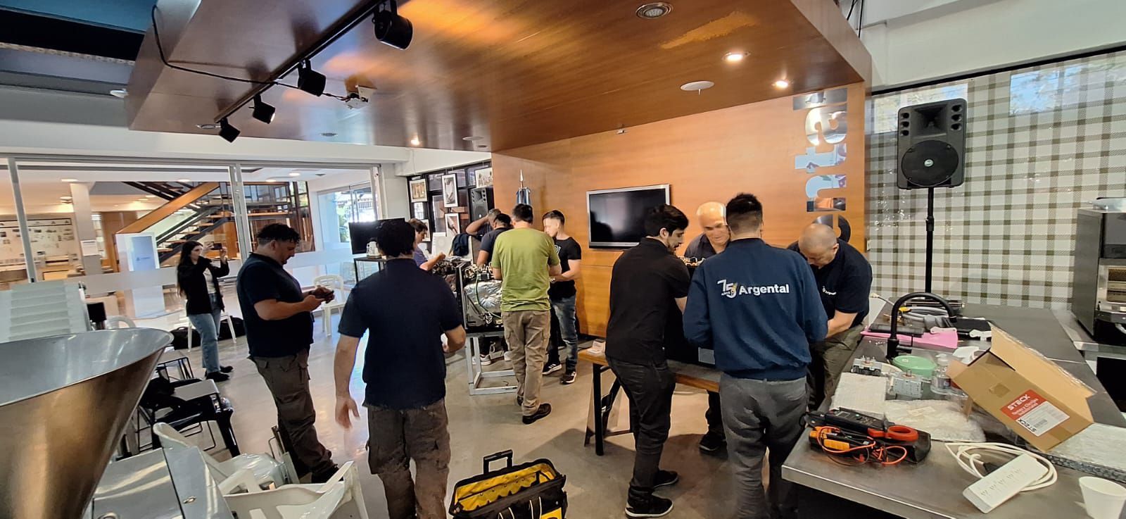 Pessoas se reuniram dentro de um espaço comercial moderno, perto de um bar. Algumas seguravam câmeras.